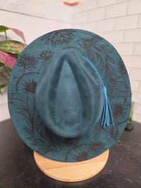 Blue hat with floral patterns on a wooden block against a neutral background
