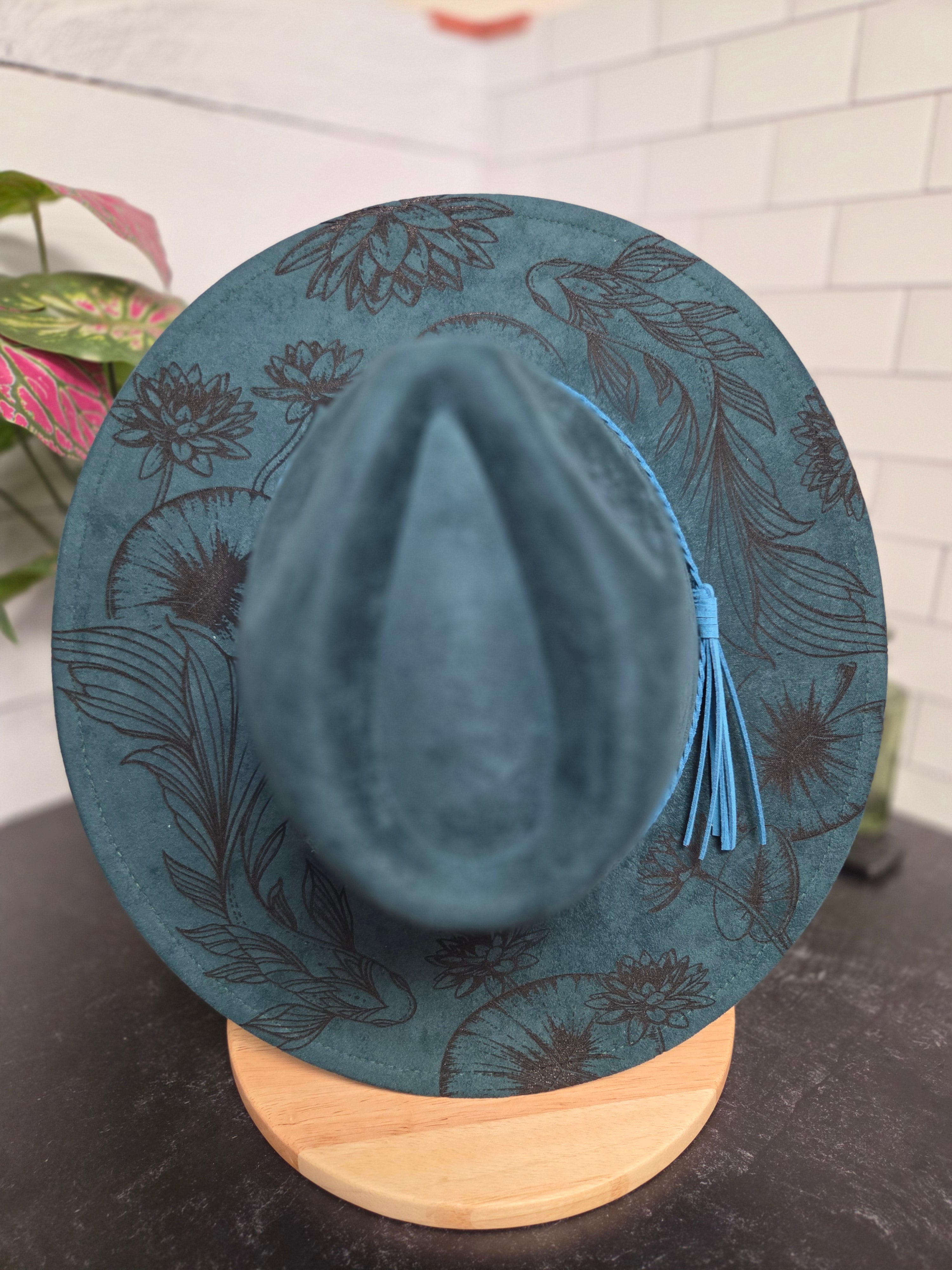 Blue hat with floral patterns on a wooden block against a neutral background