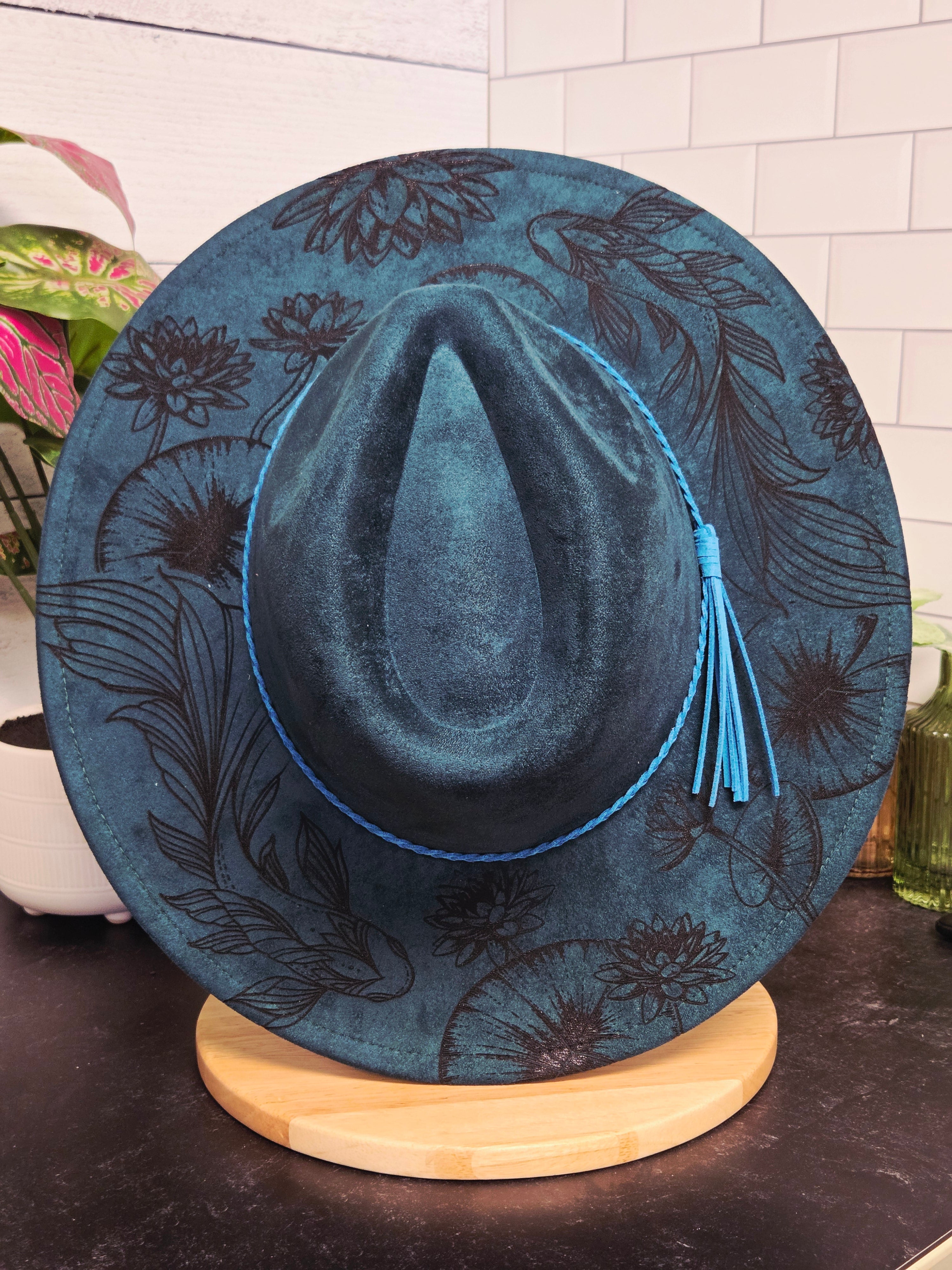 Blue embroidered hat on a wooden stand with a floral pattern