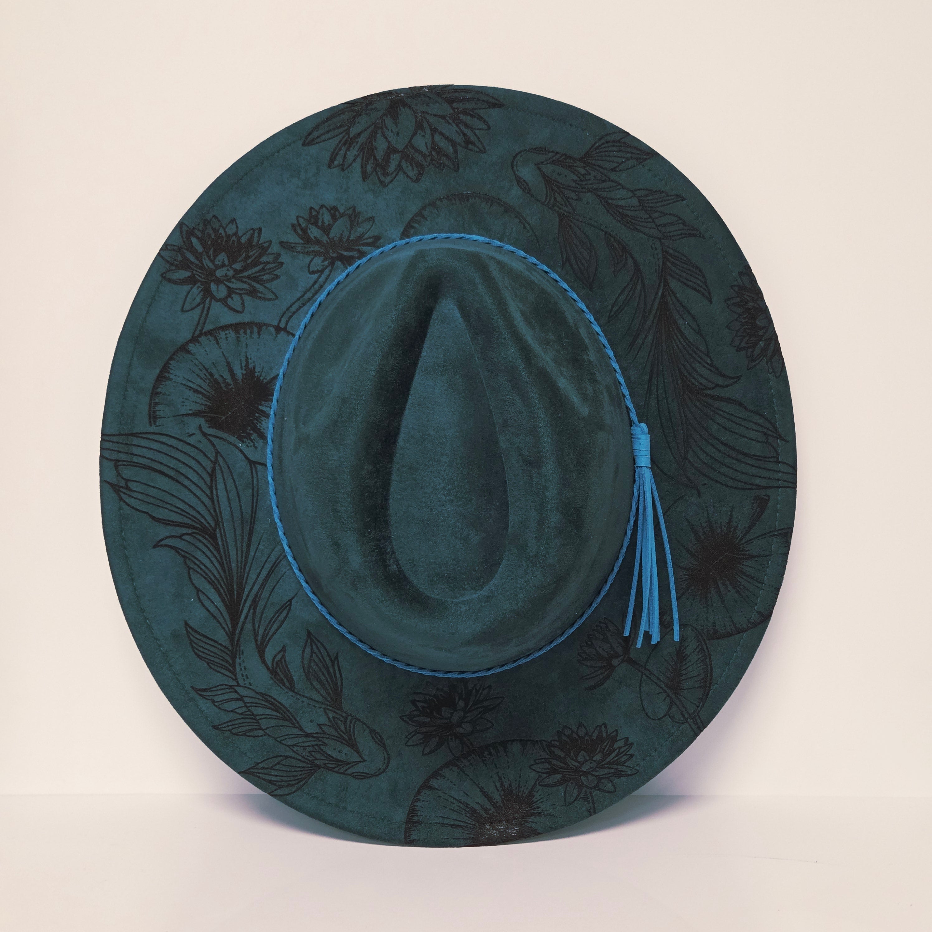 Dark green hat with floral patterns on a light beige background