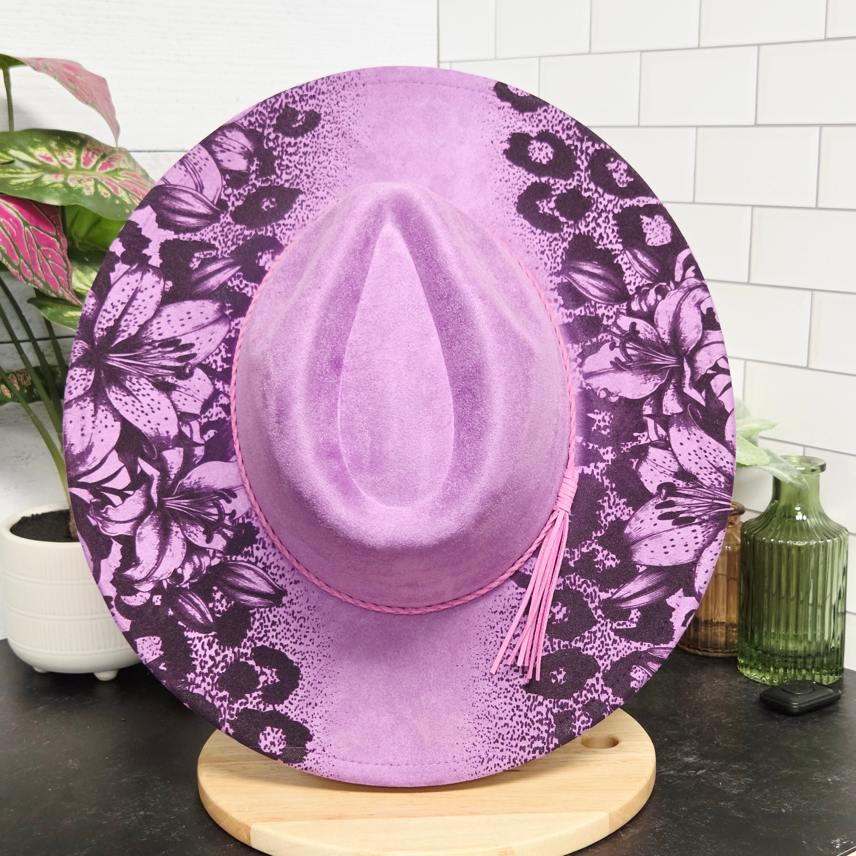 Purple floral-patterned toilet seat cover on a toilet with a tiled bathroom background.