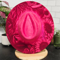 Pink floral-patterned hat on a mannequin head against a tiled wall.