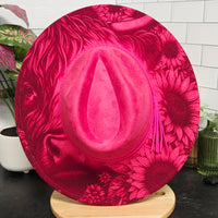 Pink floral-patterned plate on a white surface with a wooden object in the background