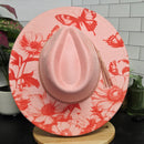 Pink hat with floral and butterfly pattern on a tiled surface