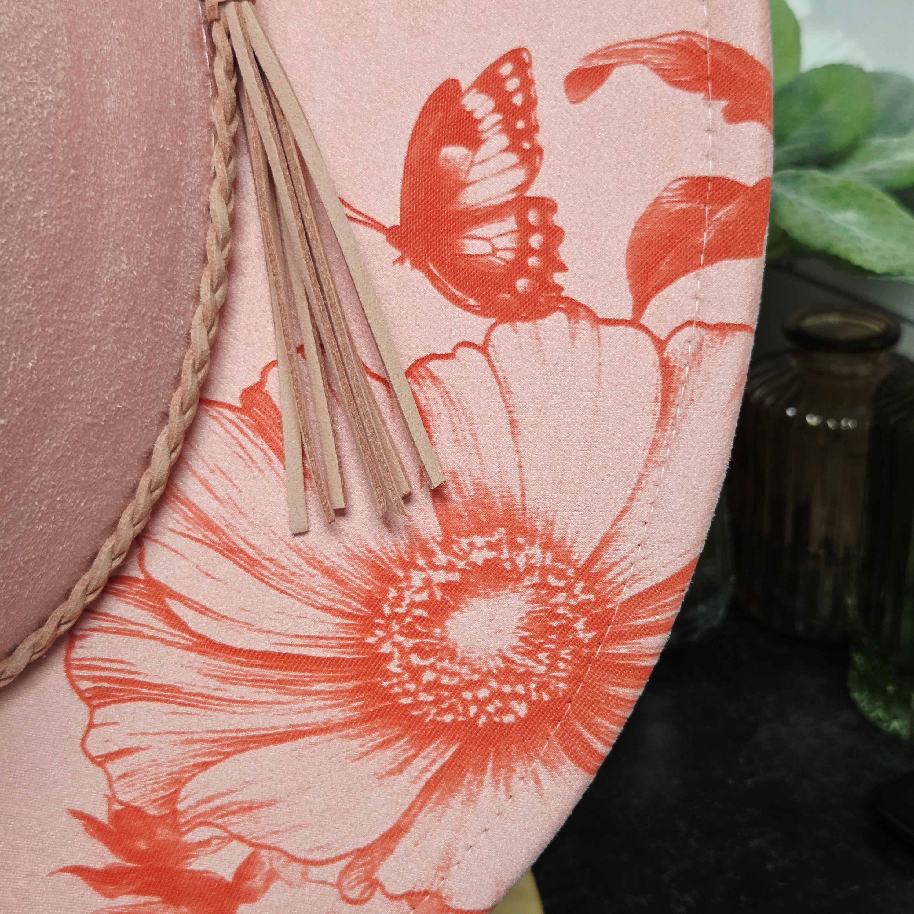 Floral and butterfly design on a pink background with dried plants.