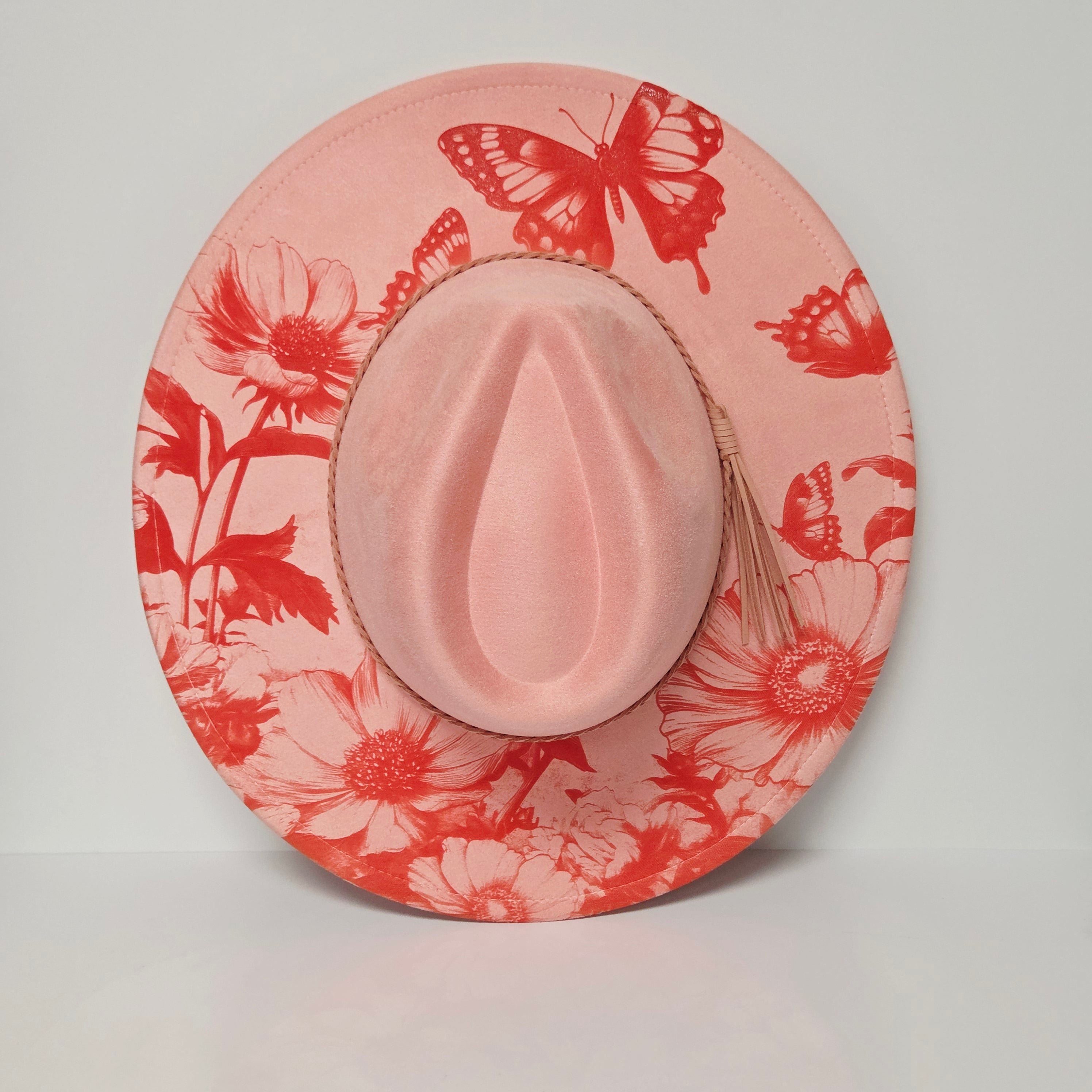 Pink hat with red floral and butterfly pattern on a light gray background