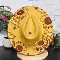 Yellow hat with sunflower and bee pattern on a white surface