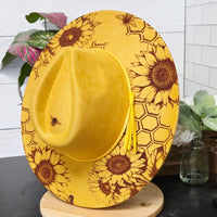 Yellow sunflower-patterned hat on a white surface with a blurred background